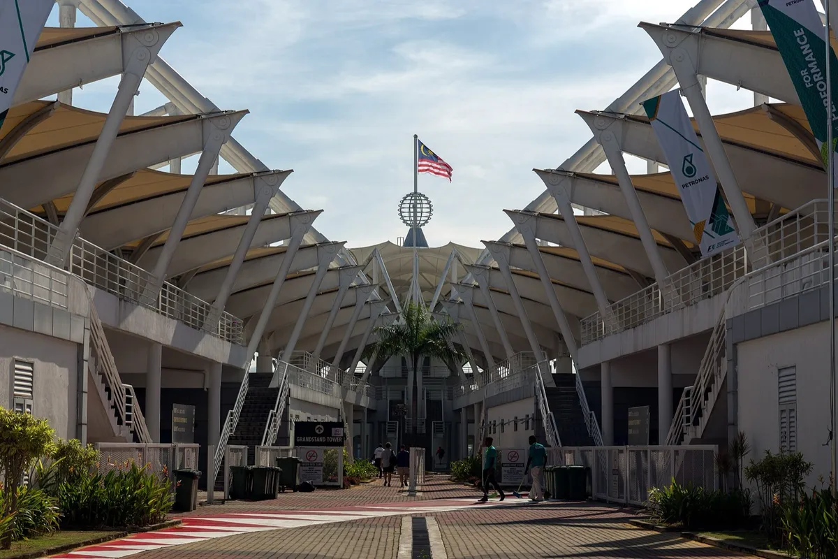 La tribune principale du circuit de Sepang en Malaisie, sous un ciel dégagé, avec le drapeau malaisien au sommet.
